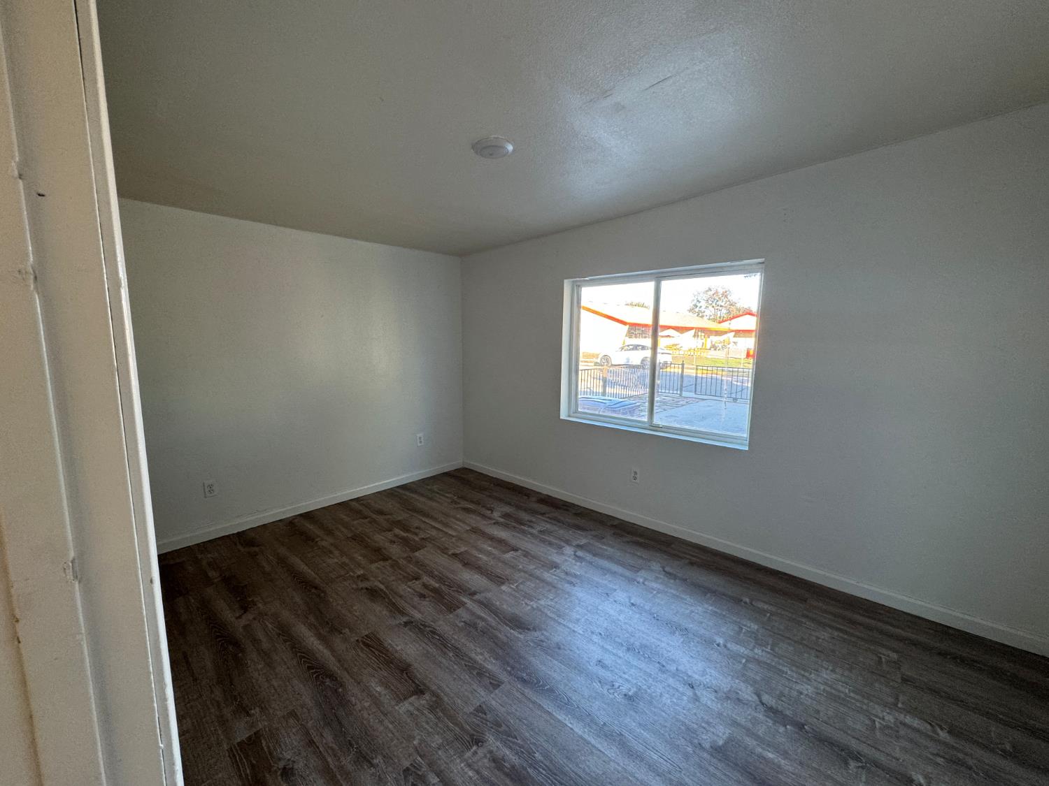 687 South 8th Street Kerman, CA 93630 - Photo 12 of 16 an empty room with wooden floor and windows