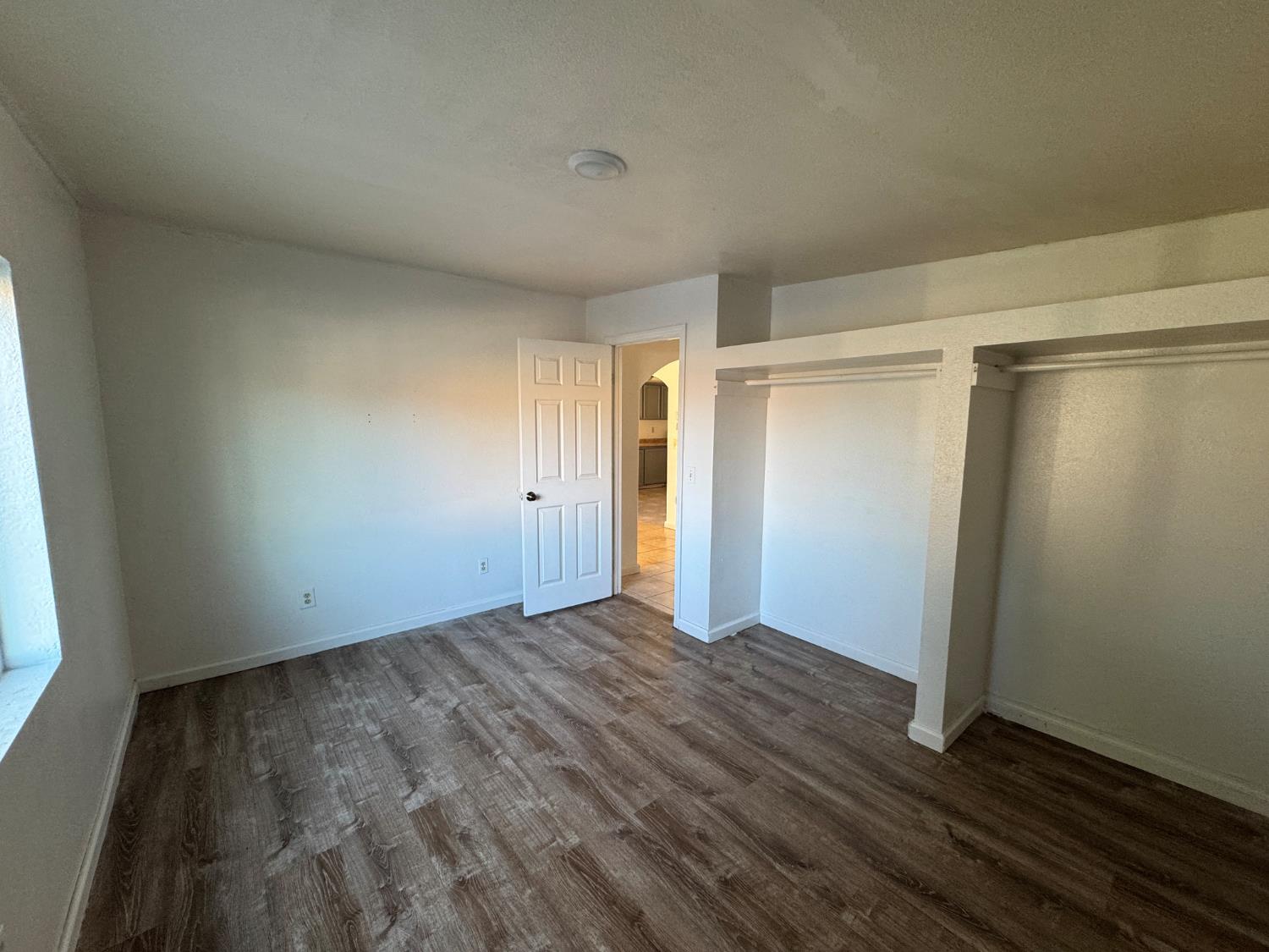 687 South 8th Street Kerman, CA 93630 - Photo 13 of 16 a view of an empty room with wooden floor and a window