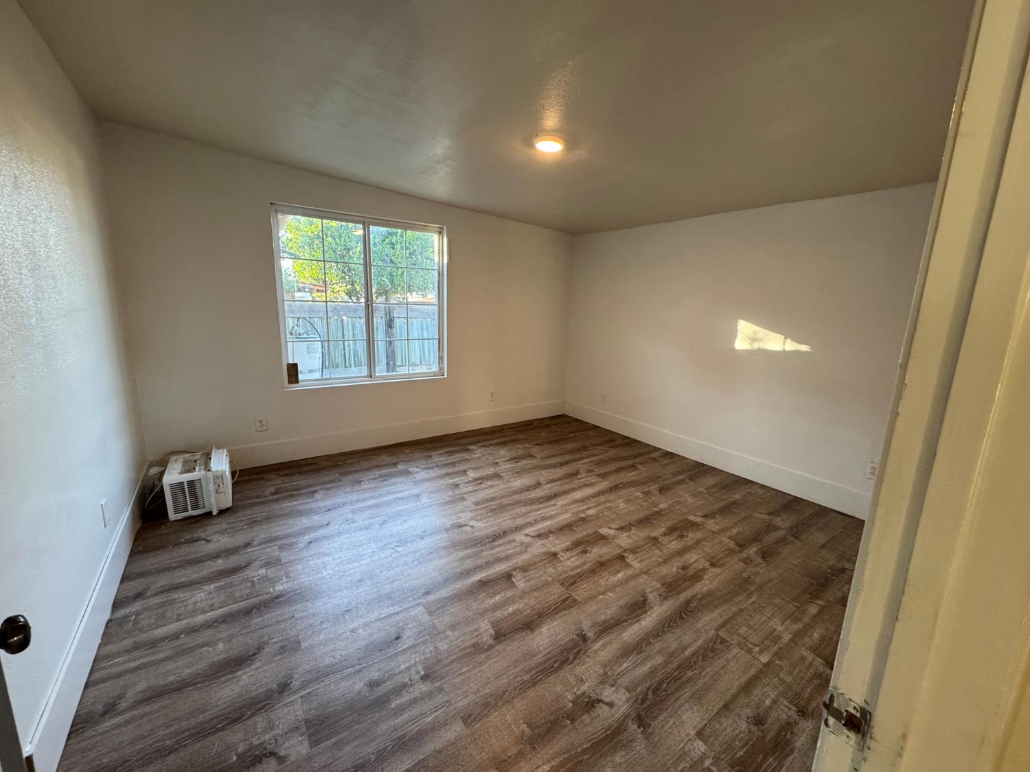 687 South 8th Street Kerman, CA 93630 - Photo 14 of 16 an empty room with wooden floor and windows