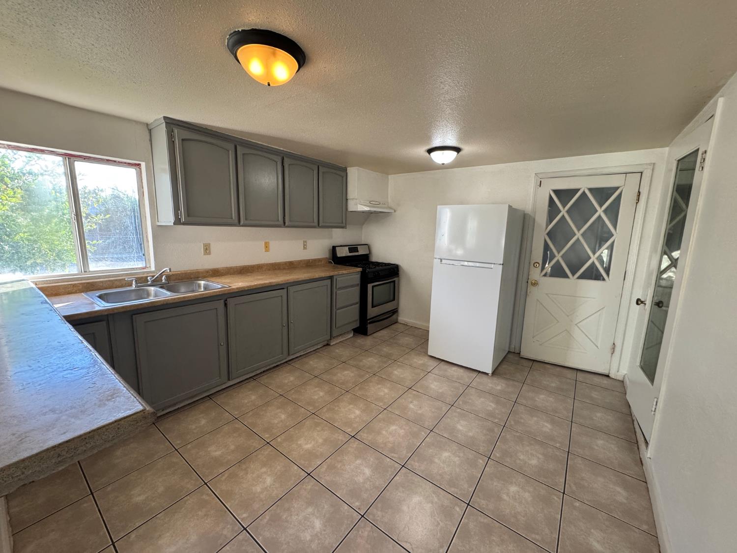 687 South 8th Street Kerman, CA 93630 - Photo 9 of 16 a kitchen with a sink a refrigerator and cabinets