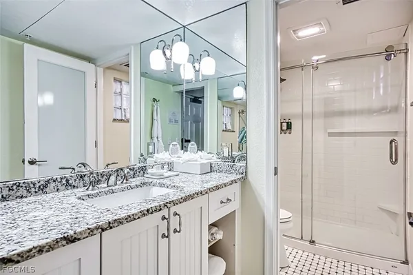 a bathroom with a granite countertop sink a mirror and a shower