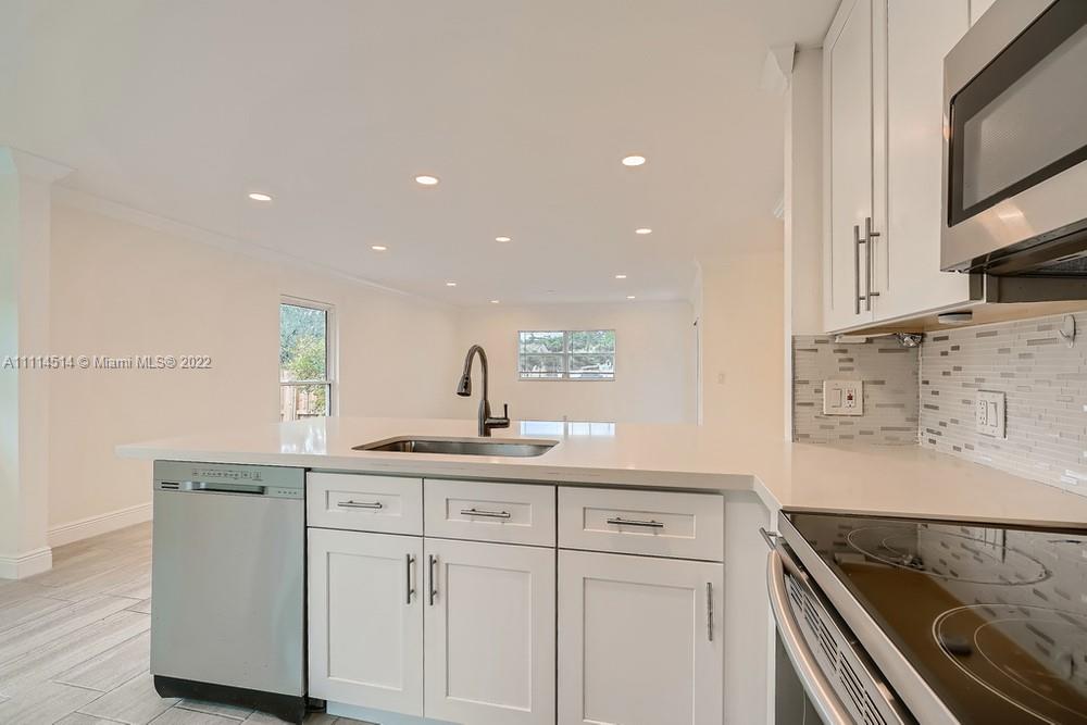 115 West Mango Road Lake Worth, FL 33467 - Photo 11 of 32 a kitchen with white cabinets sink and stove