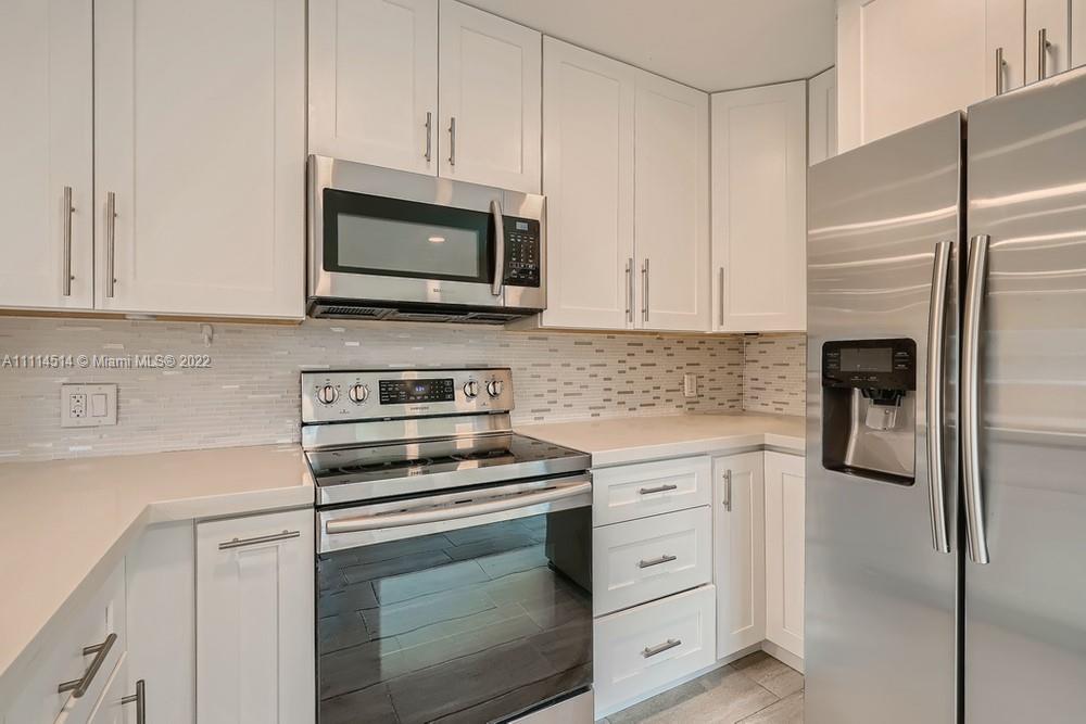 115 West Mango Road Lake Worth, FL 33467 - Photo 12 of 32 a kitchen with white cabinets and stainless steel appliances