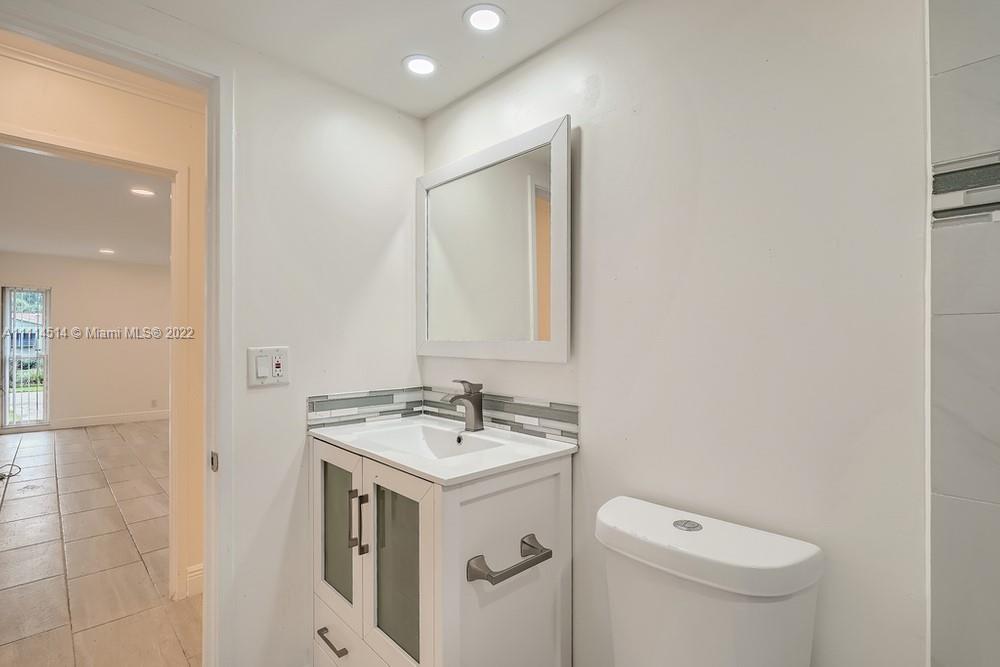 115 West Mango Road Lake Worth, FL 33467 - Photo 27 of 32 a bathroom with a sink a toilet and mirror