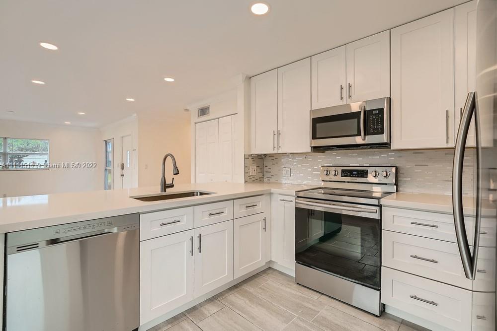 115 West Mango Road Lake Worth, FL 33467 - Photo 10 of 32 a kitchen with white cabinets stainless steel appliances and sink