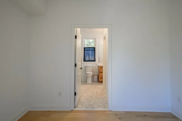 a view of a hallway with wooden floor and a bathroom