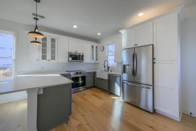 a kitchen with kitchen island a refrigerator wooden floor and a stove top oven
