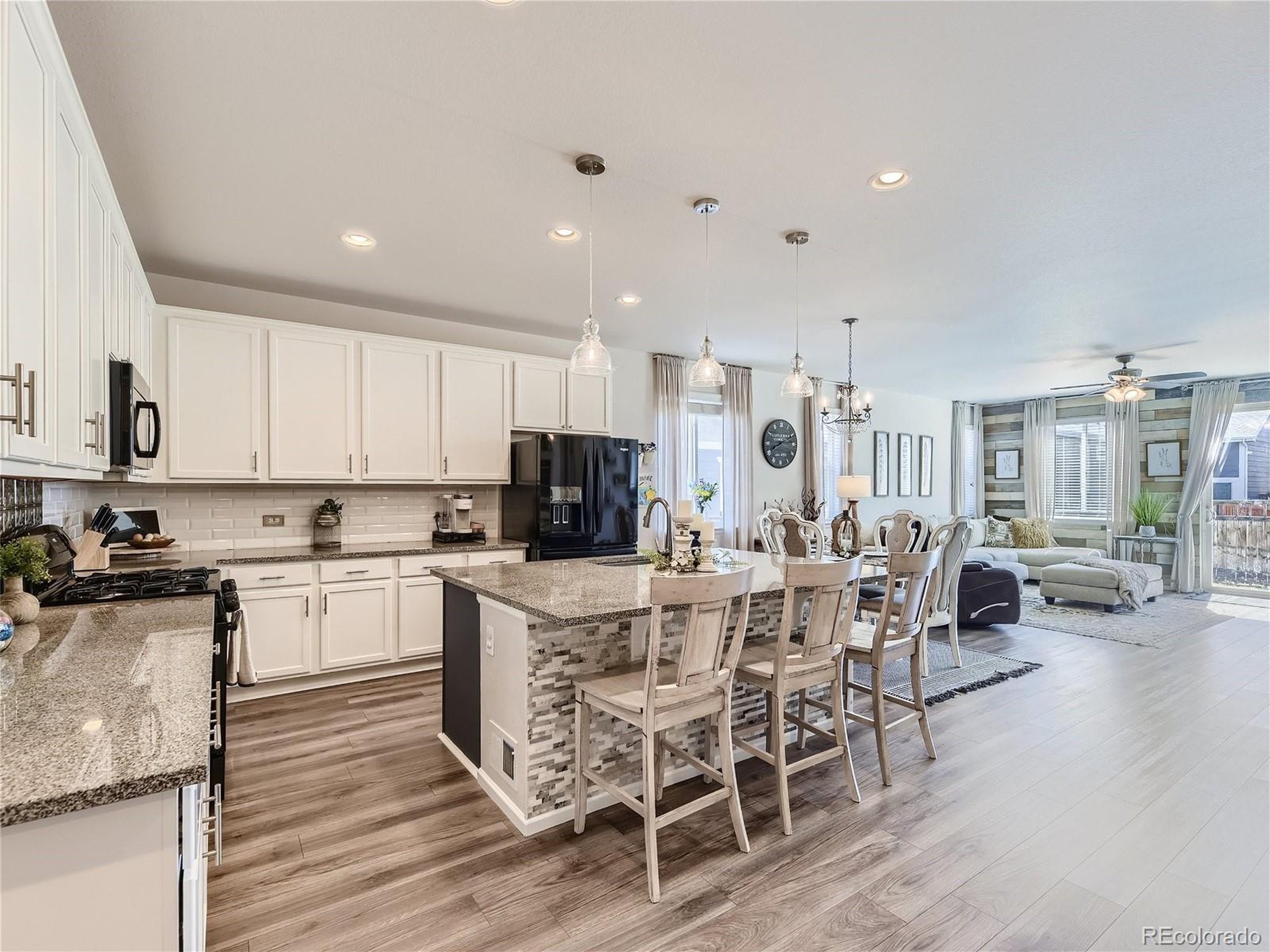 a view of a kitchen with kitchen island a dining table chairs stainless steel appliances and cabinets