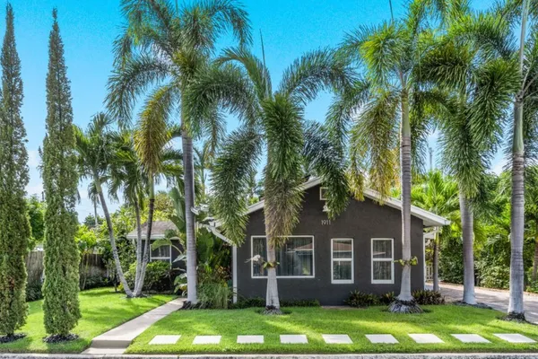 a front view of a building with garden and trees