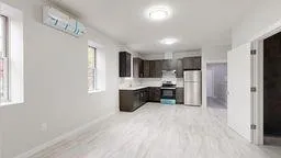 a large white kitchen with a refrigerator a sink dishwasher and a fireplace with wooden floor