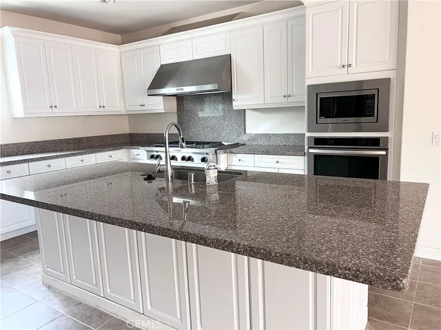 a kitchen with granite countertop a sink a stove and cabinets