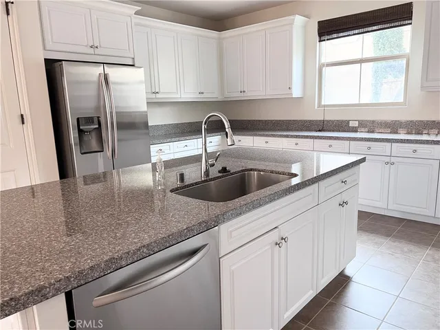 a kitchen with stainless steel appliances granite countertop a sink a window and refrigerator