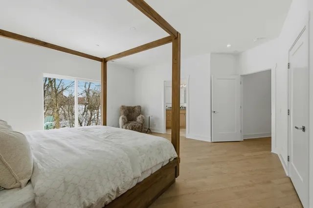 a view of a hallway with wooden floor and a bathroom