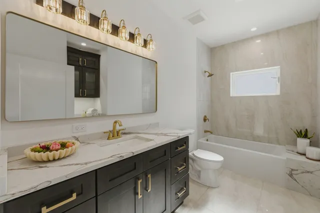 a bathroom with a granite countertop sink a toilet a mirror and shower