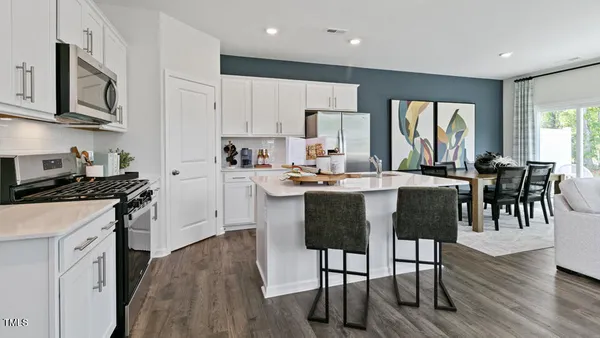 a kitchen with stainless steel appliances kitchen island granite countertop a stove a sink a dining table and chairs