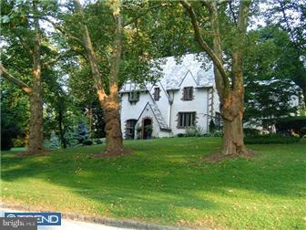 a view of a white house next to a yard with big trees
