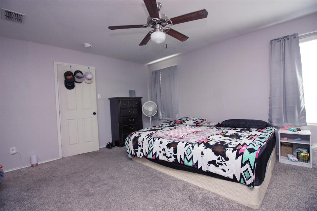 12609 Carpenter Lane Rhome, TX 76078 - Photo 5 of 29 Carpeted room featuring a ceiling fan, white paneled door, and windows with curtain rods