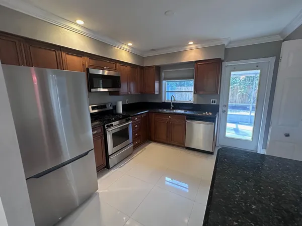 a kitchen with stainless steel appliances a refrigerator a sink a stove a microwave a sink and cabinets