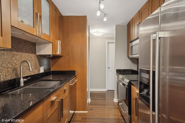 a kitchen with granite countertop a sink stainless steel appliances and cabinets