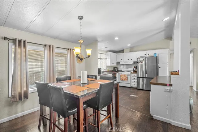 a dining room with stainless steel appliances kitchen island granite countertop a dining table chairs and wooden floor