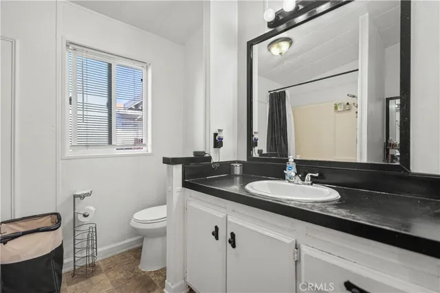 a bathroom with a granite countertop toilet sink and mirror