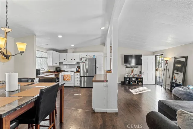a living room with stainless steel appliances furniture a rug and a kitchen view