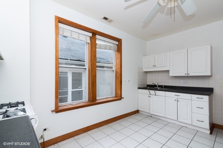 819 South Carpenter Street, Unit 3R Chicago, IL 60607 - Photo 5 of 10 a kitchen with granite countertop white cabinets and window
