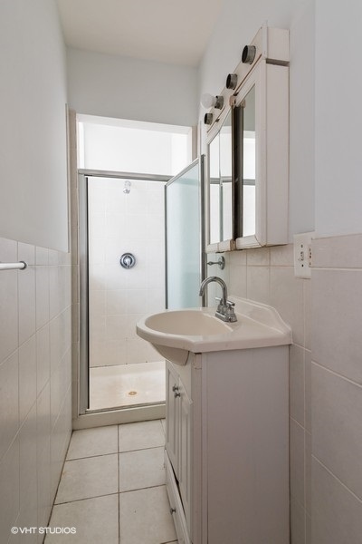 819 South Carpenter Street, Unit 3R Chicago, IL 60607 - Photo 10 of 10 a bathroom with a granite countertop sink a mirror and shower