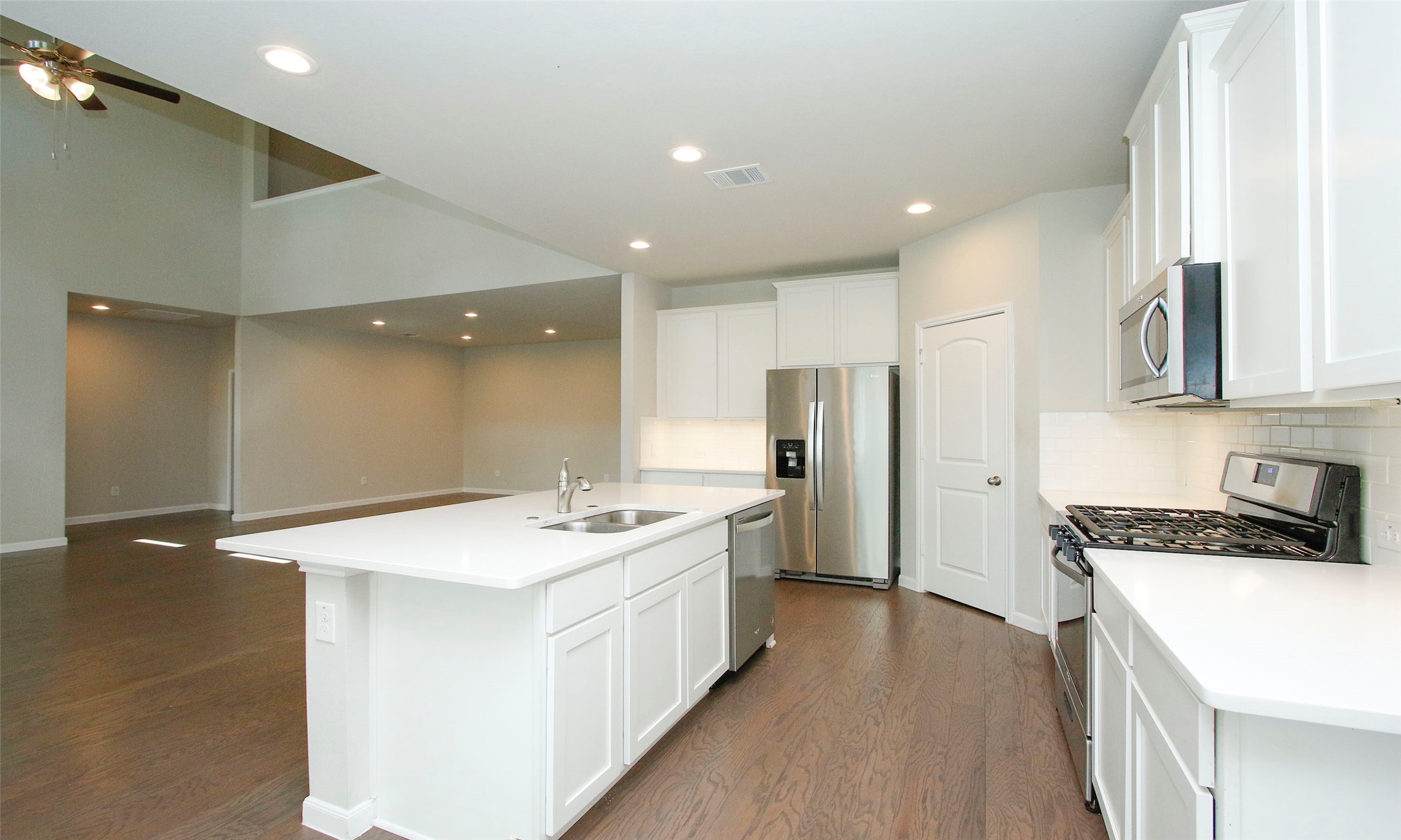 14120 Sand Ridge Court Conroe, TX 77384 - Photo 17 of 43 a kitchen with stainless steel appliances a stove a sink a refrigerator and white cabinets with wooden floor