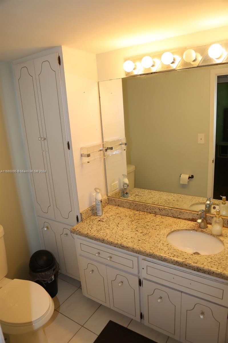 800 Northeast 195th Street, Unit 501 Miami, FL 33179 - Photo 25 of 39 a bathroom with a granite countertop sink and a mirror