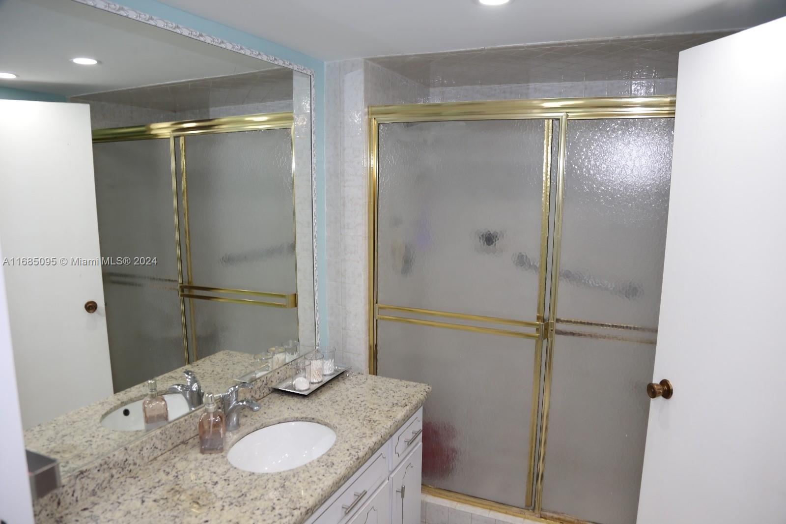 800 Northeast 195th Street, Unit 501 Miami, FL 33179 - Photo 26 of 39 a bathroom with a granite countertop shower sink vanity and mirror