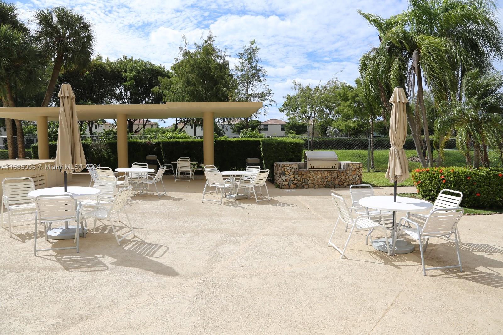 800 Northeast 195th Street, Unit 501 Miami, FL 33179 - Photo 34 of 39 a view of a patio with a table and chairs and couches under an umbrella