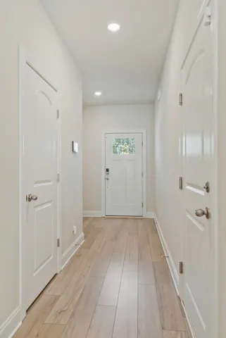 a view of a hallway with wooden floor and a bathroom