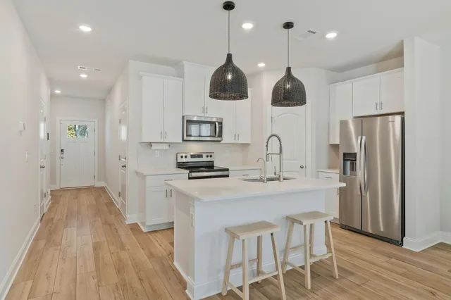 a kitchen with stainless steel appliances granite countertop a sink a stove a refrigerator and island with wooden floor