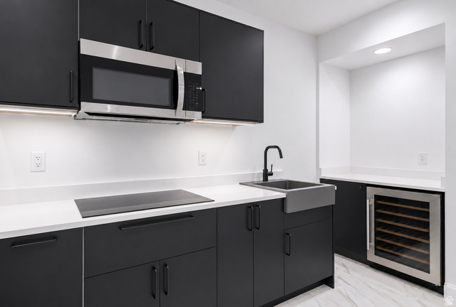 1429 Chateau Ridge Way Sandy, UT 84092 - Photo 15 of 22 Modern kitchen featuring matte black cabinetry, integrated stainless steel microwave, induction cooktop, and a matte black farmhouse sink with a matching faucet