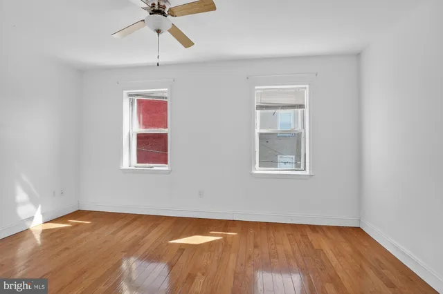 a view of empty room with wooden floor and fan