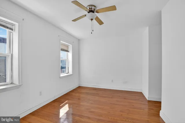 a view of empty room with wooden floor and fan