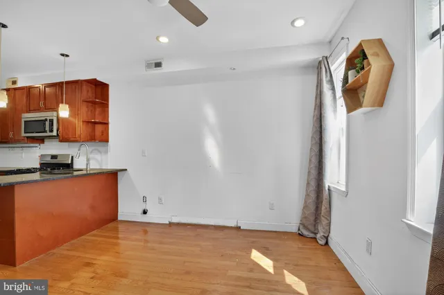 a view of a kitchen with fridge and wooden floor
