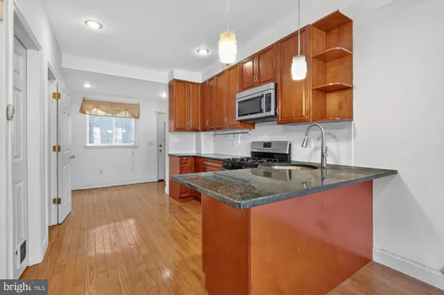 a kitchen with granite countertop a sink stainless steel appliances and cabinets