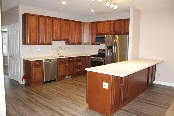 a kitchen with stainless steel appliances a sink a stove a refrigerator cabinets and wooden floor