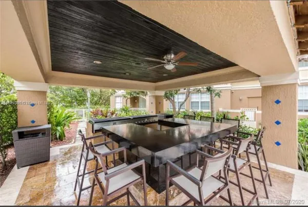 a view of a patio with a table and chairs under an umbrella with a barbeque