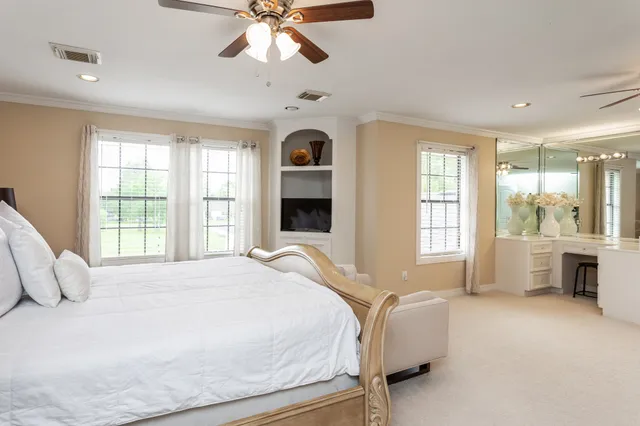 a bedroom with a large bed and a chandelier fan