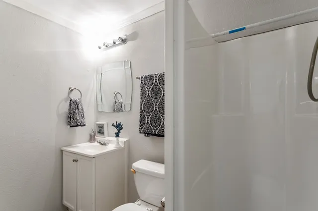 a bathroom with a toilet sink vanity and shower