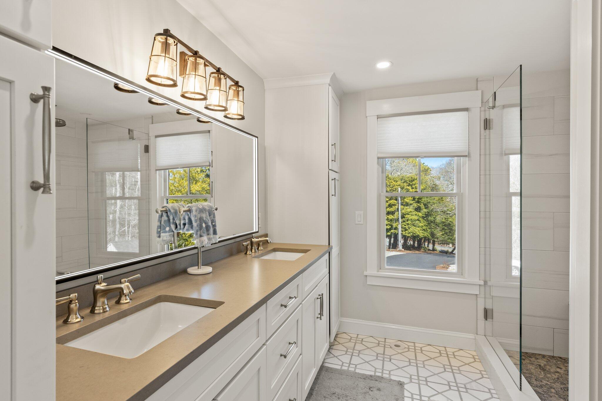 87 Oyster Pond Road Falmouth, MA 02540 - Photo 30 of 105 a bathroom with a sink double vanity mirror and a bathtub next to a window