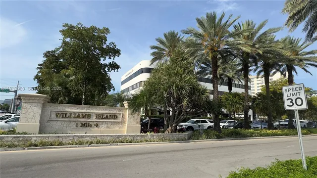 a view of a street with a building and palm trees