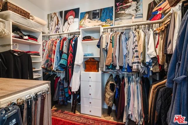 a view of walk in closet with clothes and shoes