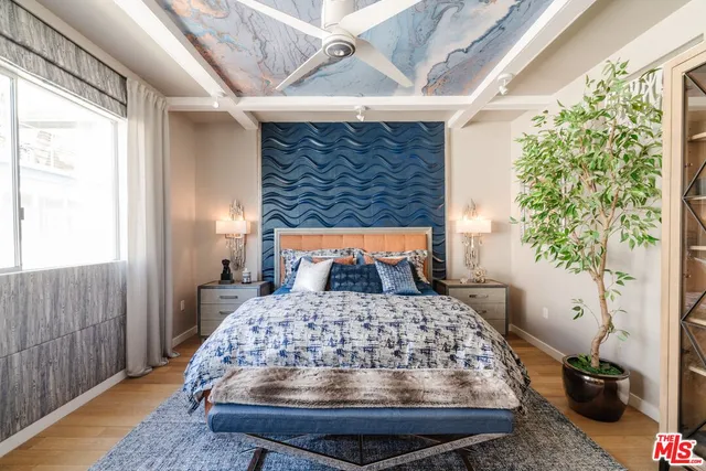 a bed sitting in a bedroom next to a window with potted plants