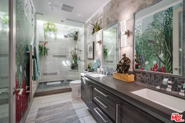 a bathroom with double vanity sinks a large mirror and a shower