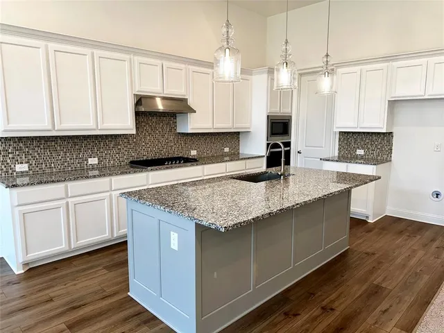 a kitchen with granite countertop a sink a counter top space and cabinets