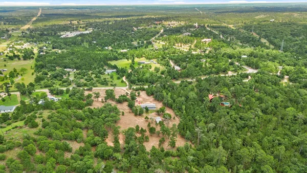 an aerial view of residential houses with outdoor space and trees